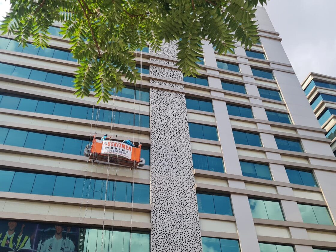 Yüksek katlı iş merkezinde asılı sepetle cam cephe temizliği